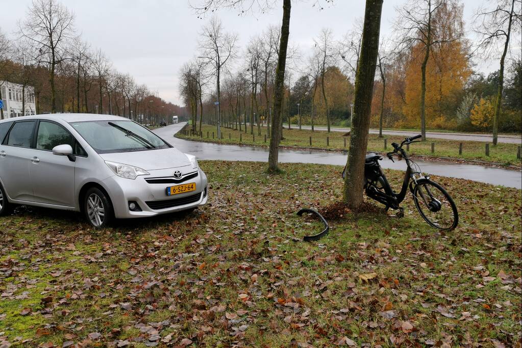 Fietser bekneld onder auto