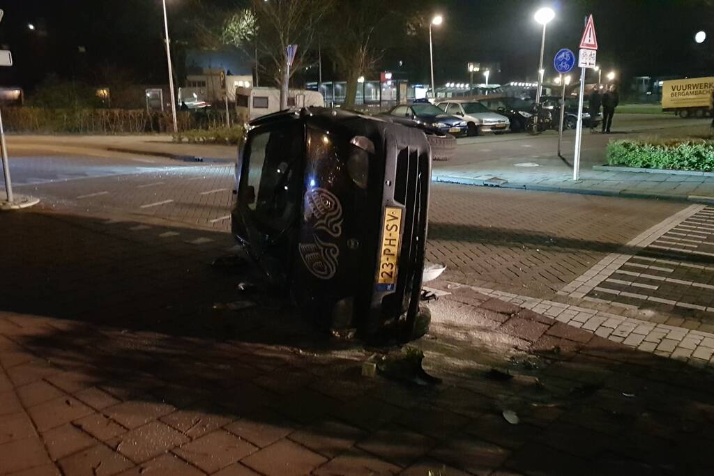 Auto op zijn kant na botsing met lantaarnpaal