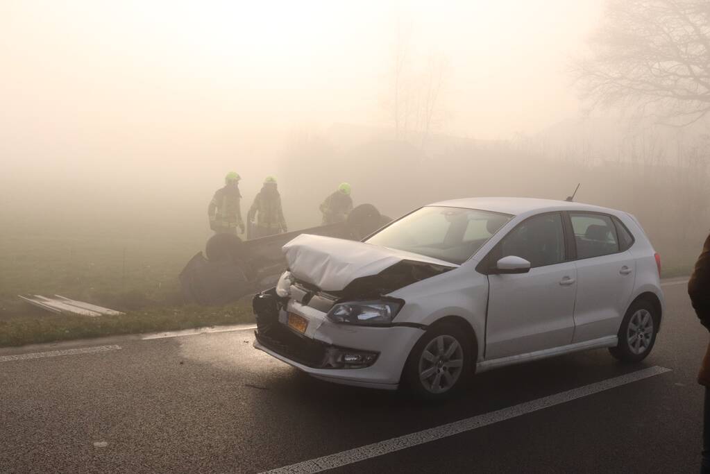 Auto op kop in sloot na botsing met andere auto