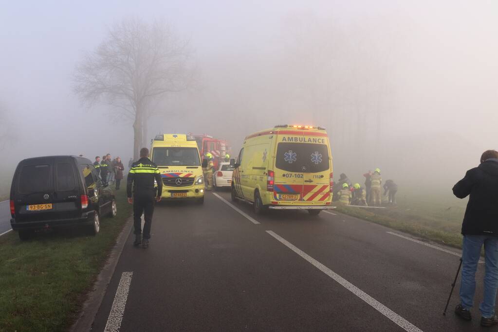 Auto op kop in sloot na botsing met andere auto