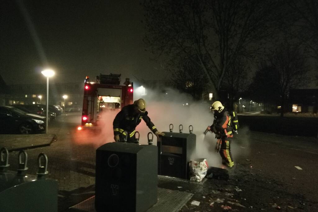 Vuurwerkresten in de brand naast papiercontainer