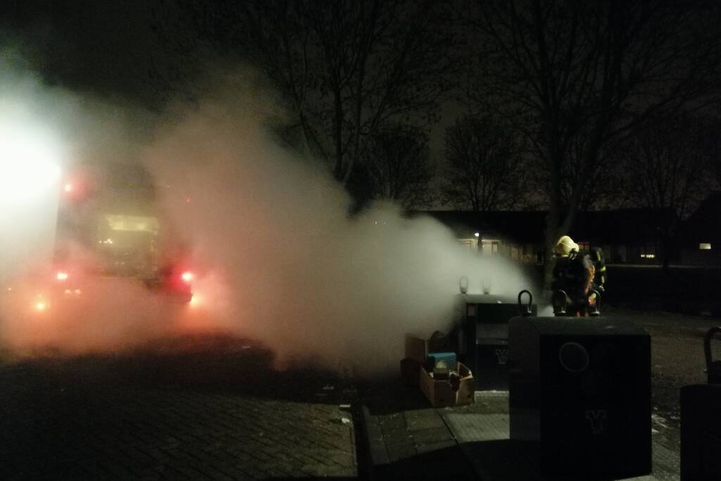 Vuurwerkresten in de brand naast papiercontainer