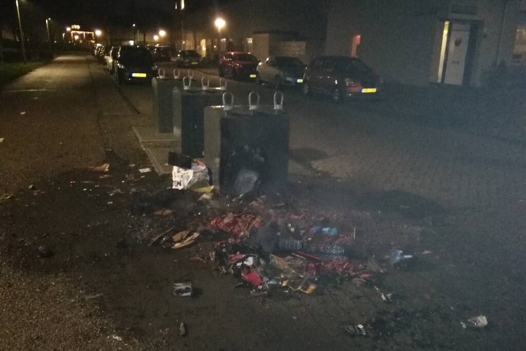 Vuurwerkresten in de brand naast papiercontainer