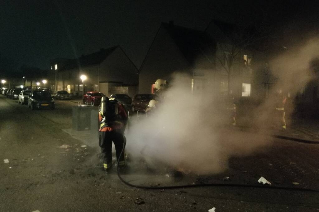 Vuurwerkresten in de brand naast papiercontainer