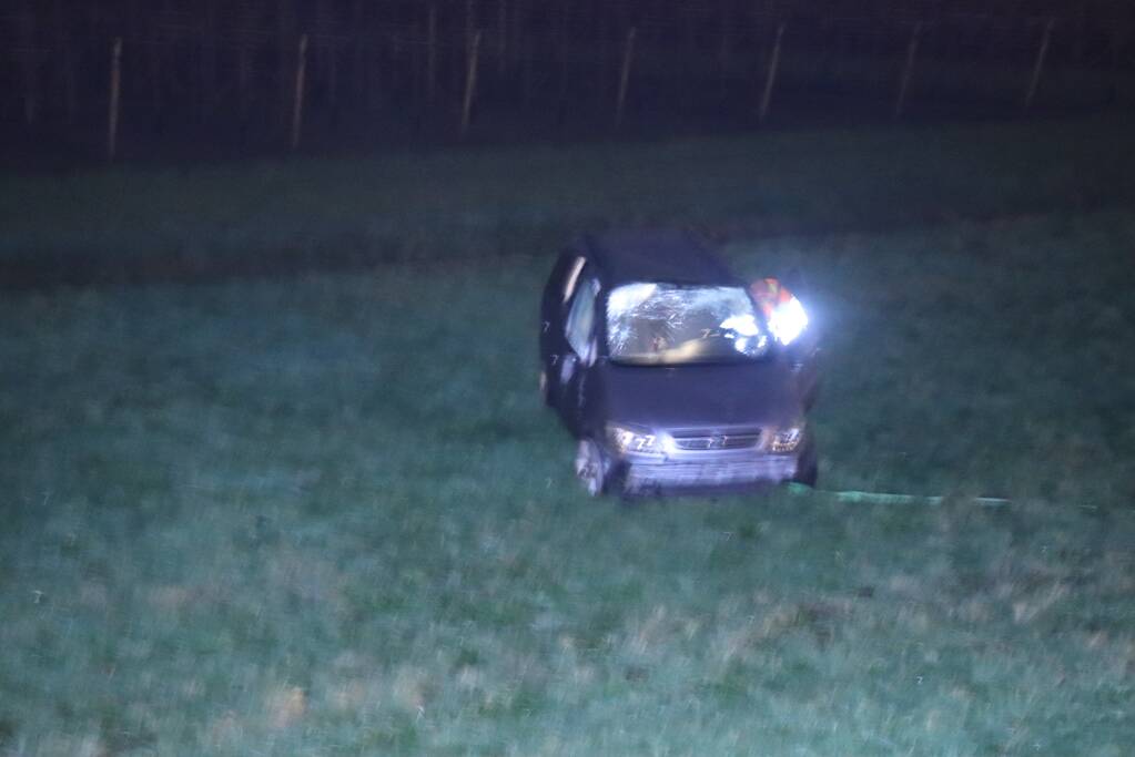 Auto vliegt uit de bocht op afrit en belandt in weiland