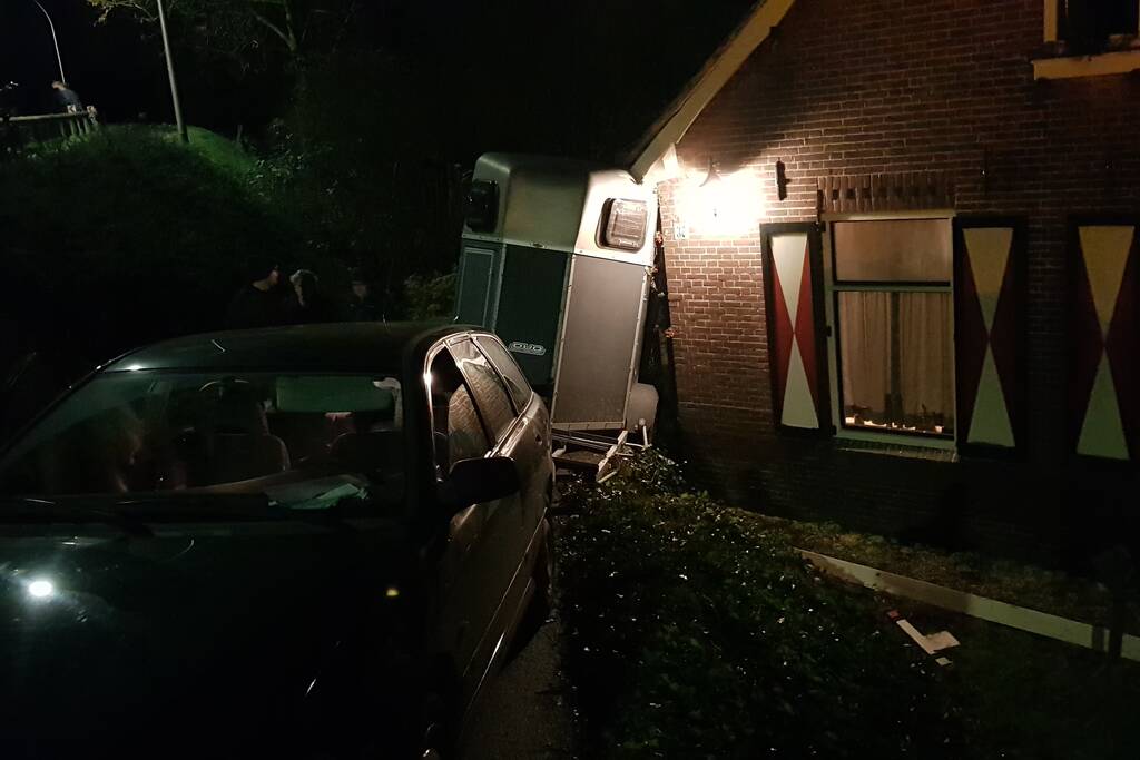 Auto met paardentrailer botst tegen huis.