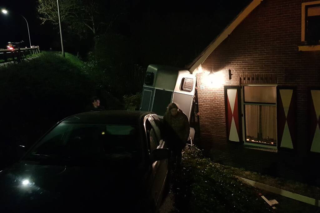 Auto met paardentrailer botst tegen huis.