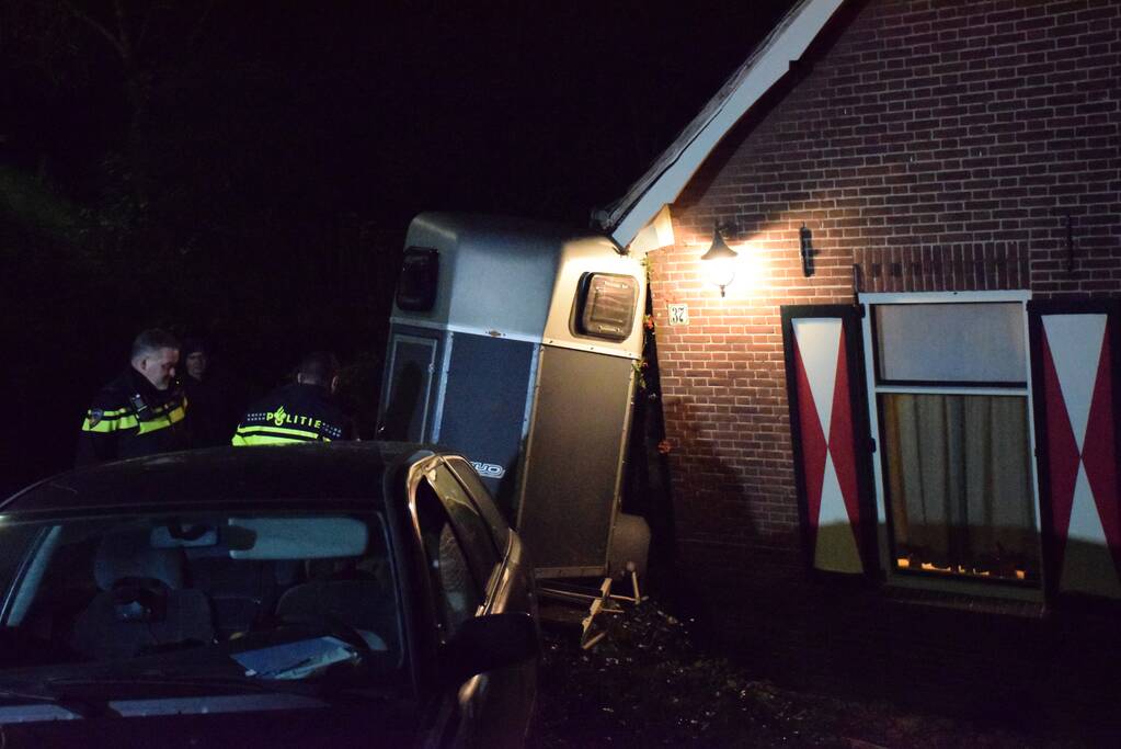 Auto met paardentrailer botst tegen huis.