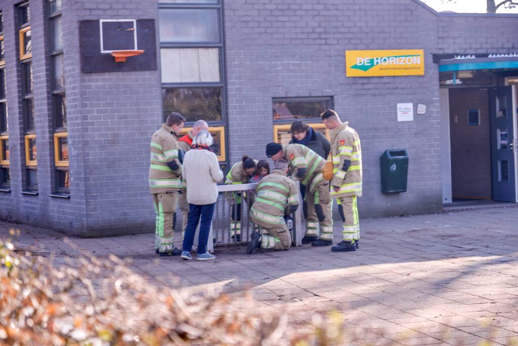 Meisje bekneld met been in doeltje op schoolplein