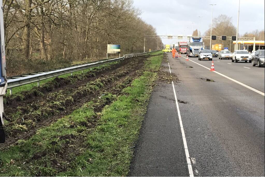 Vrachtwagen belandt in berm tegen vangrail