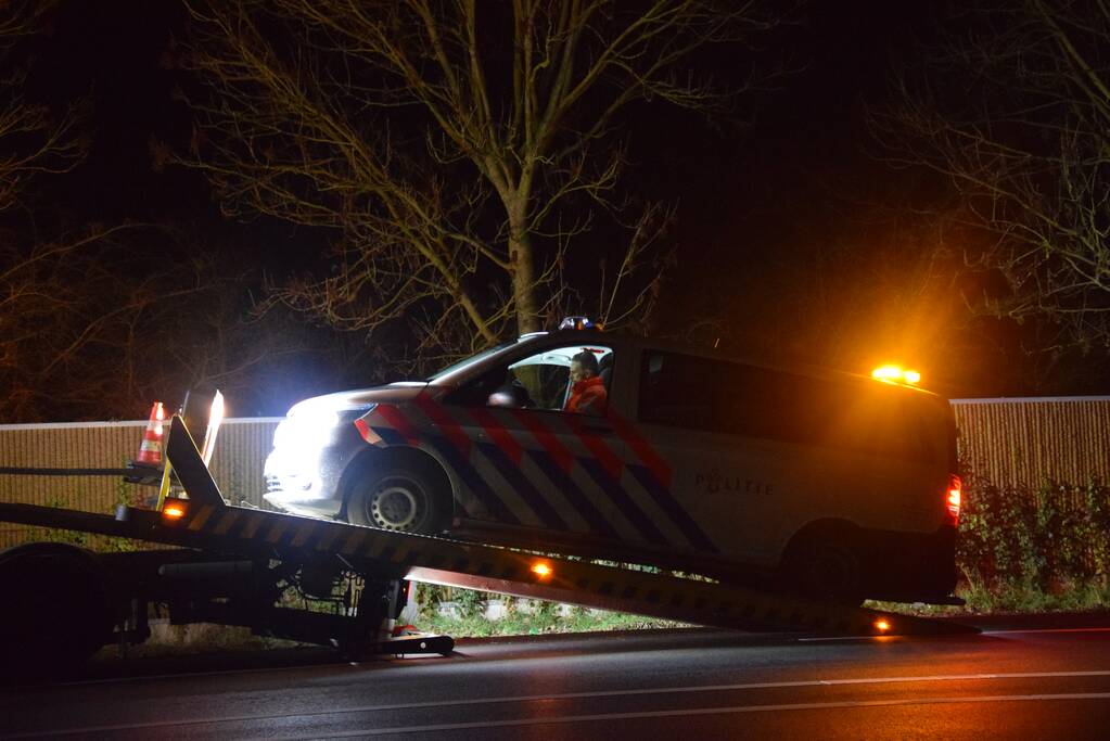 Politieauto en personenauto beschadigd door stenen op rijbaan
