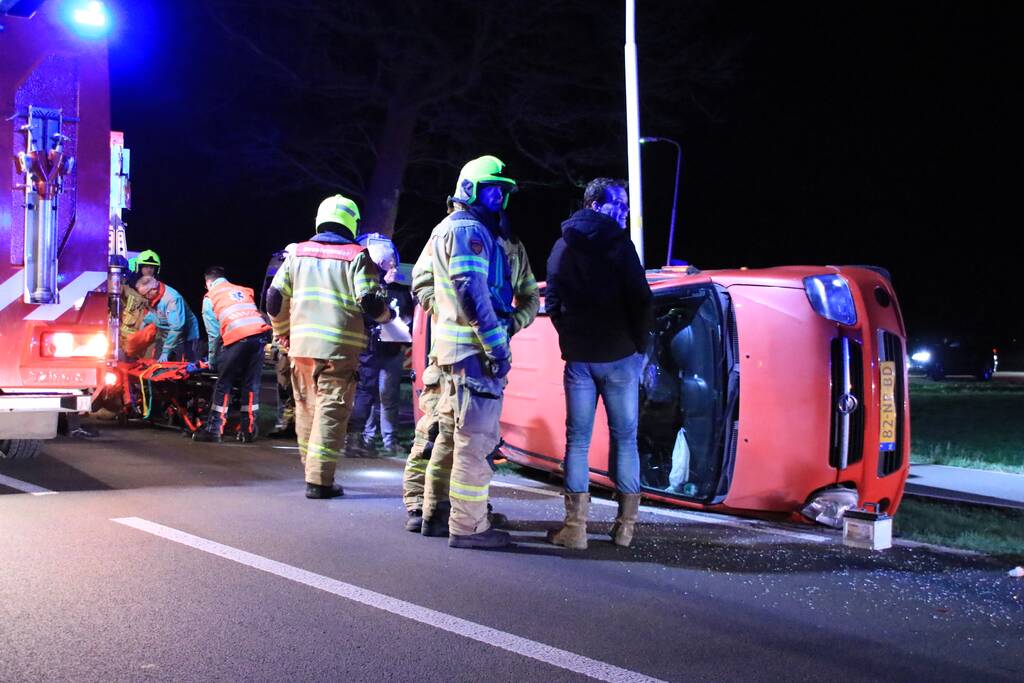 Auto op zijn kant na botsing tegen lantarenpaal