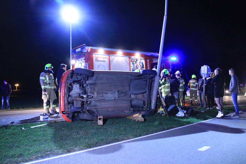 Auto op zijn kant na botsing tegen lantarenpaal