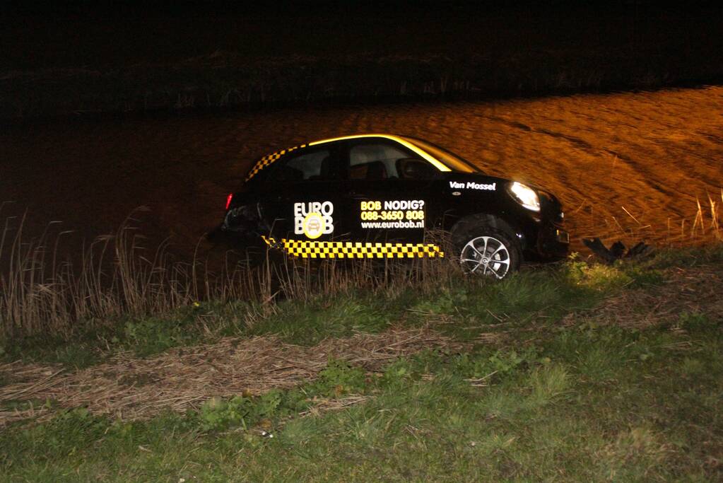 Auto belandt in sloot na botsing met hek
