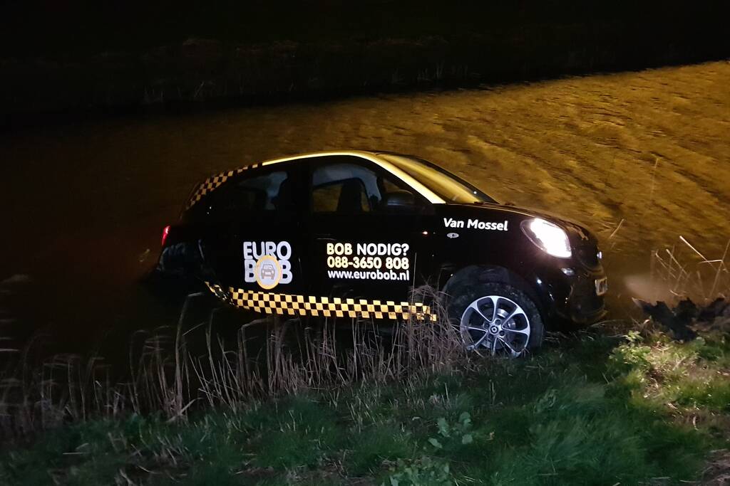 Auto belandt in sloot na botsing met hek