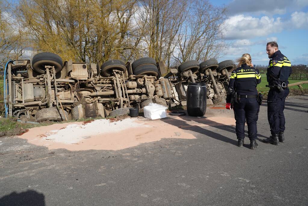 Vrachtwagen met zand van dijk gekanteld