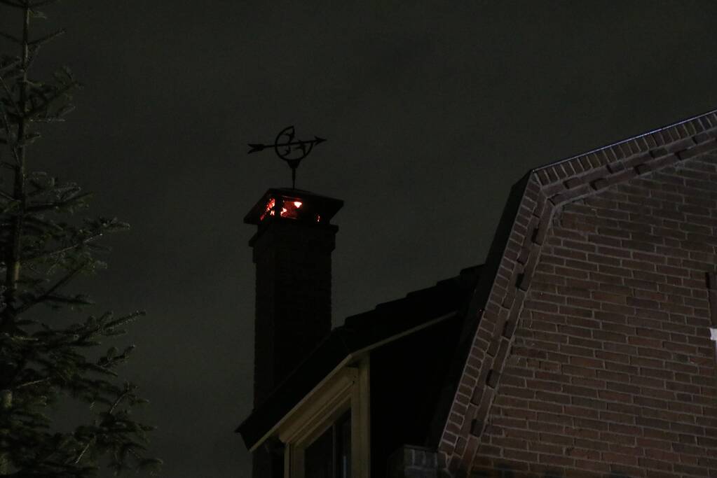 Vlammen slaan uit schoorsteen van woning