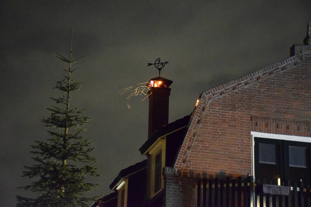 Vlammen slaan uit schoorsteen van woning