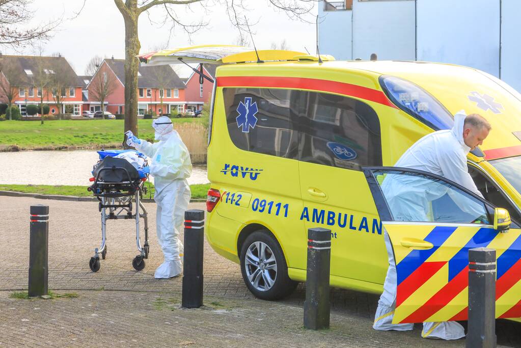 Mannen in witte pakken halen vermoedelijke coronapatiënt uit huis