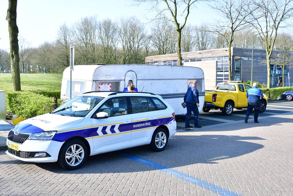 Handhaving sleept caravan met protesttekst weg van parkeerterrein gemeentewerf