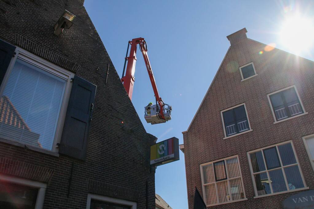 Brandweer verwijdert losliggende dakpannen winkelpand
