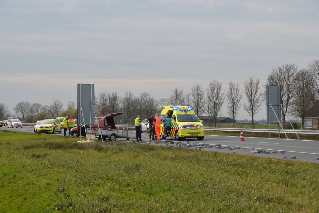 Bestelbus met aanhanger slaat over de kop