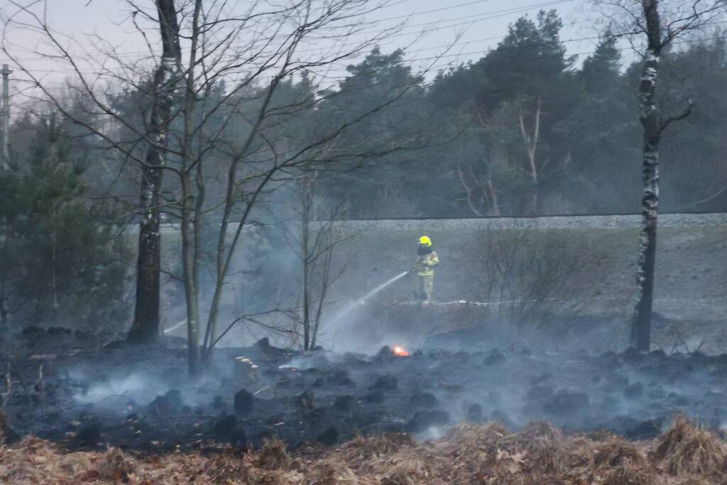 Groot stuk bosschage langs spoor in brand