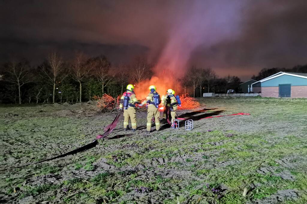 Berg met takken in weiland vatte vlam