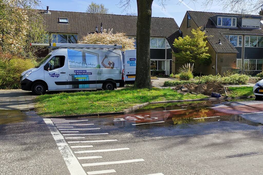Water stroomt de weg op na leidingbreuk