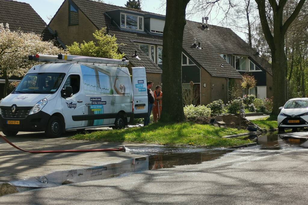 Water stroomt de weg op na leidingbreuk