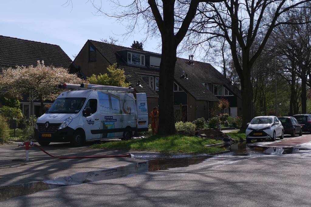Water stroomt de weg op na leidingbreuk