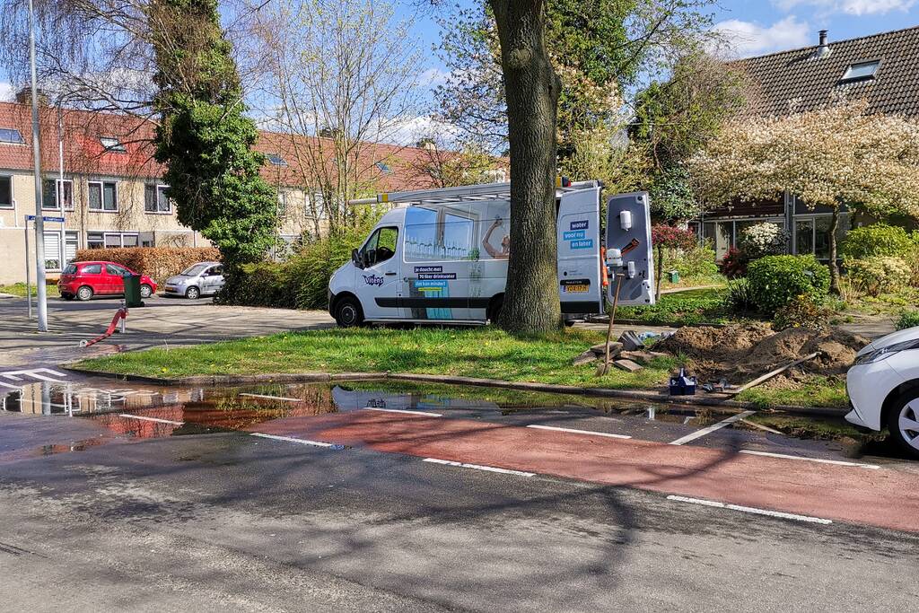 Water stroomt de weg op na leidingbreuk