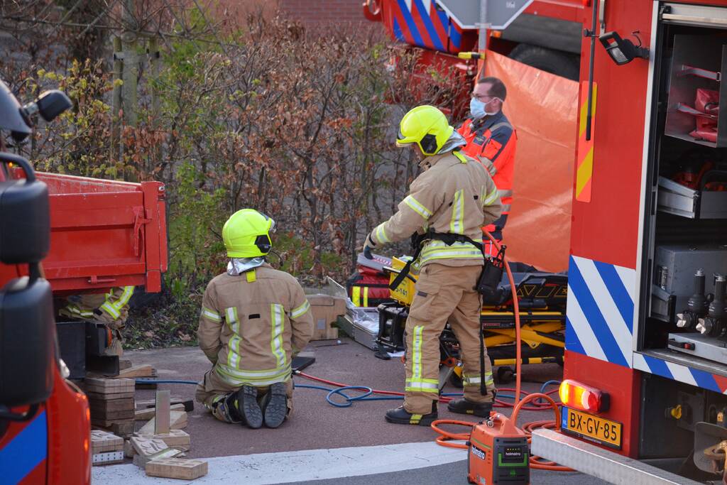 Man bekneld onder as van bedrijfswagen