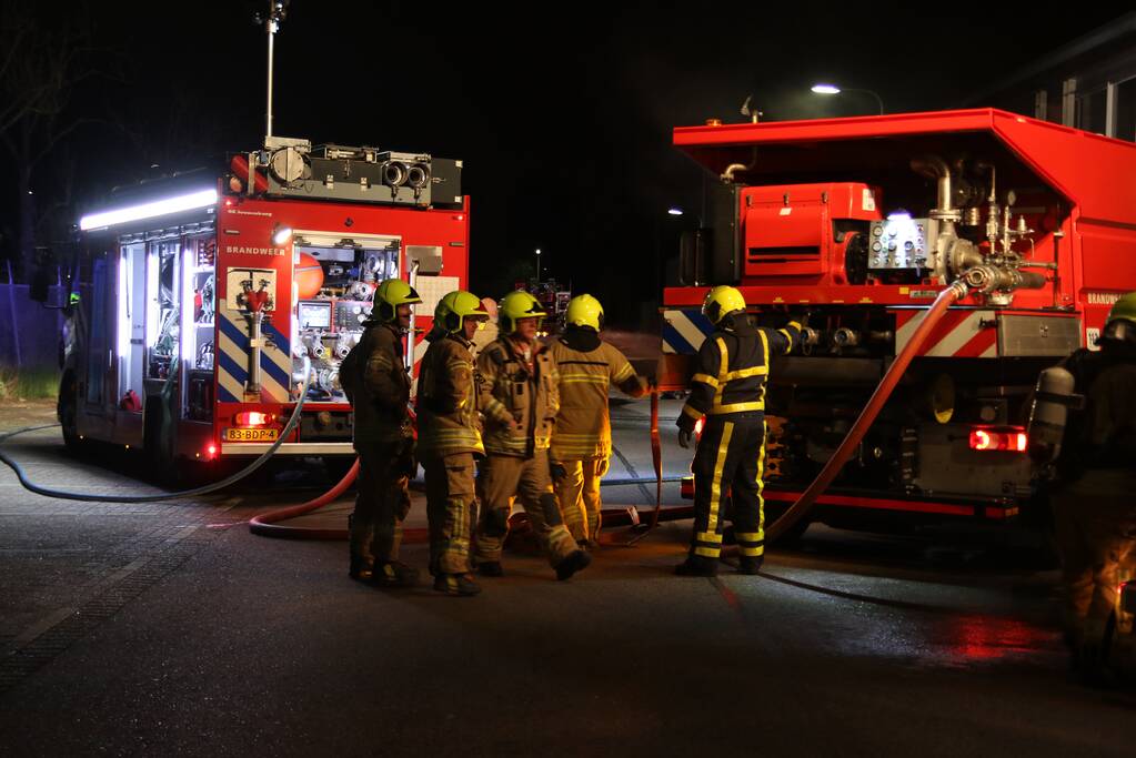 Meerdere voertuigen in brand tegen gevel bedrijfspand