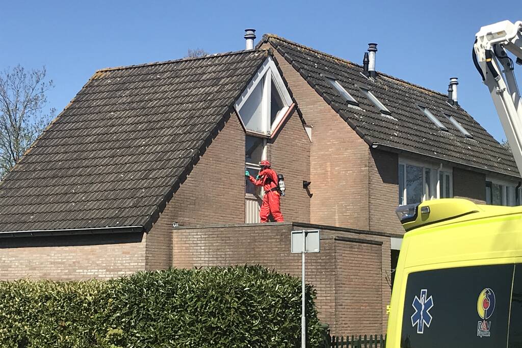 Brandweer in beschermende pakken halen persoon uit woning