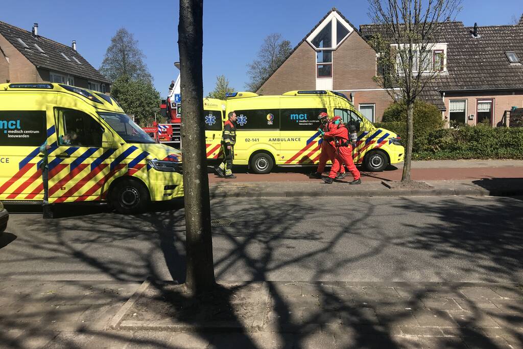 Brandweer in beschermende pakken halen persoon uit woning