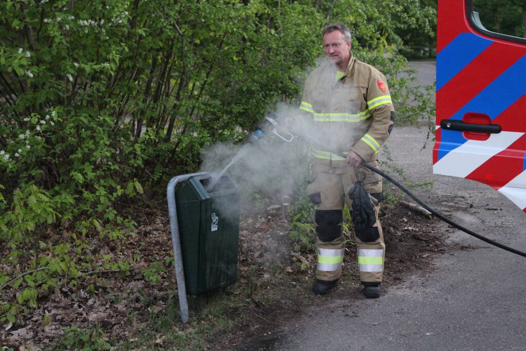 Omstanders doven vuur in prullenbak op parkeerterrein