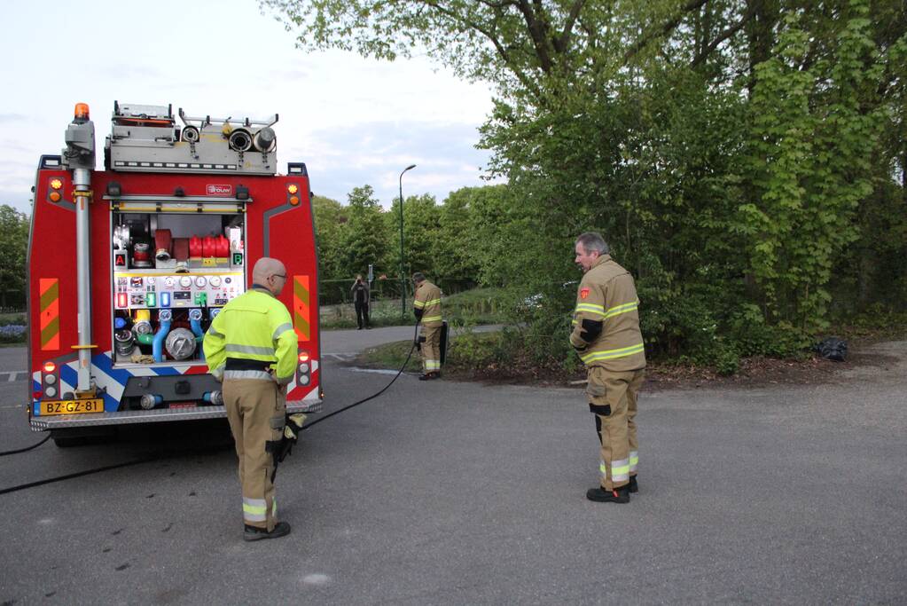 Omstanders doven vuur in prullenbak op parkeerterrein
