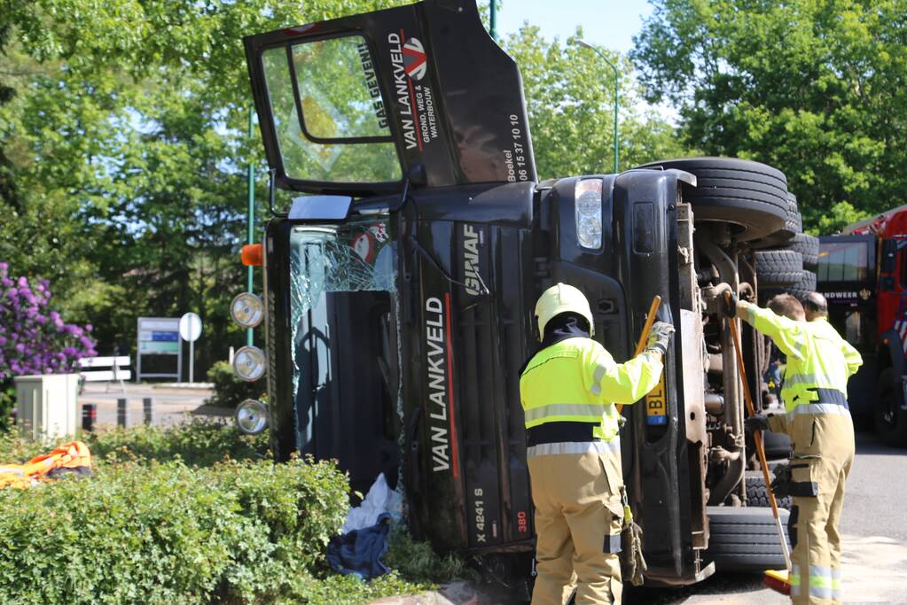 Vrachtwagen met tuinafval gekanteld op rotonde