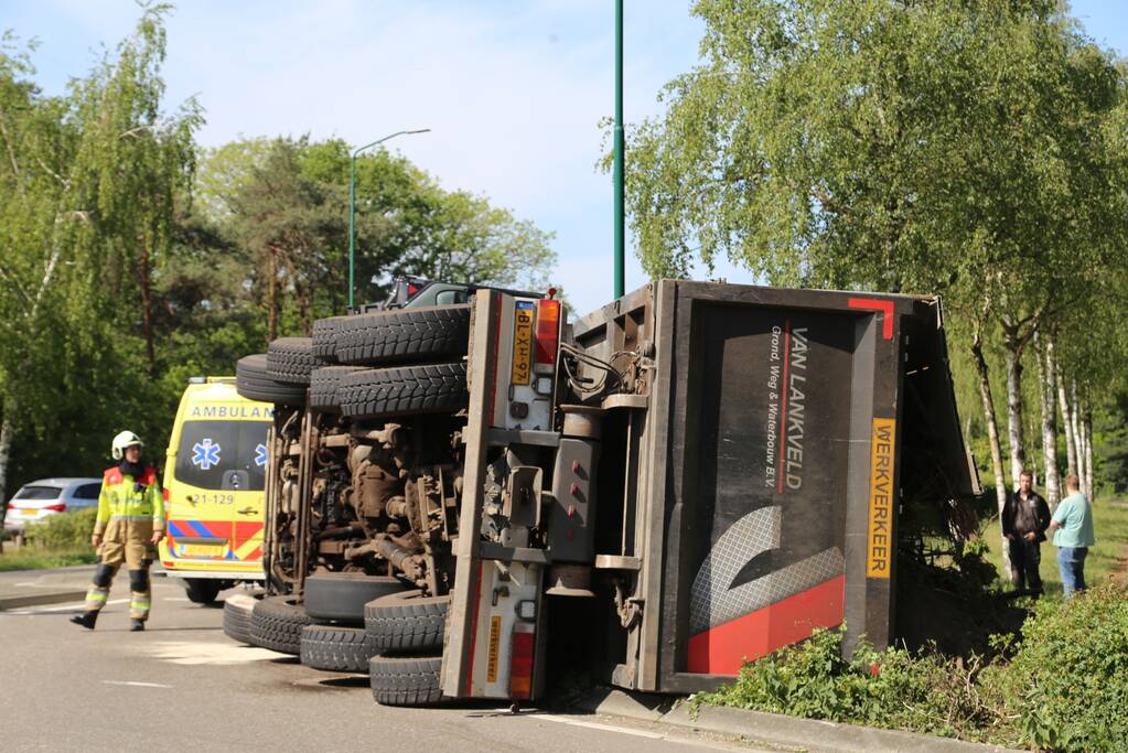 Vrachtwagen met tuinafval gekanteld op rotonde