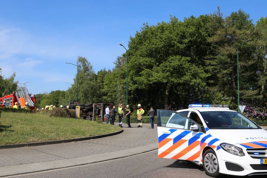 Vrachtwagen met tuinafval gekanteld op rotonde