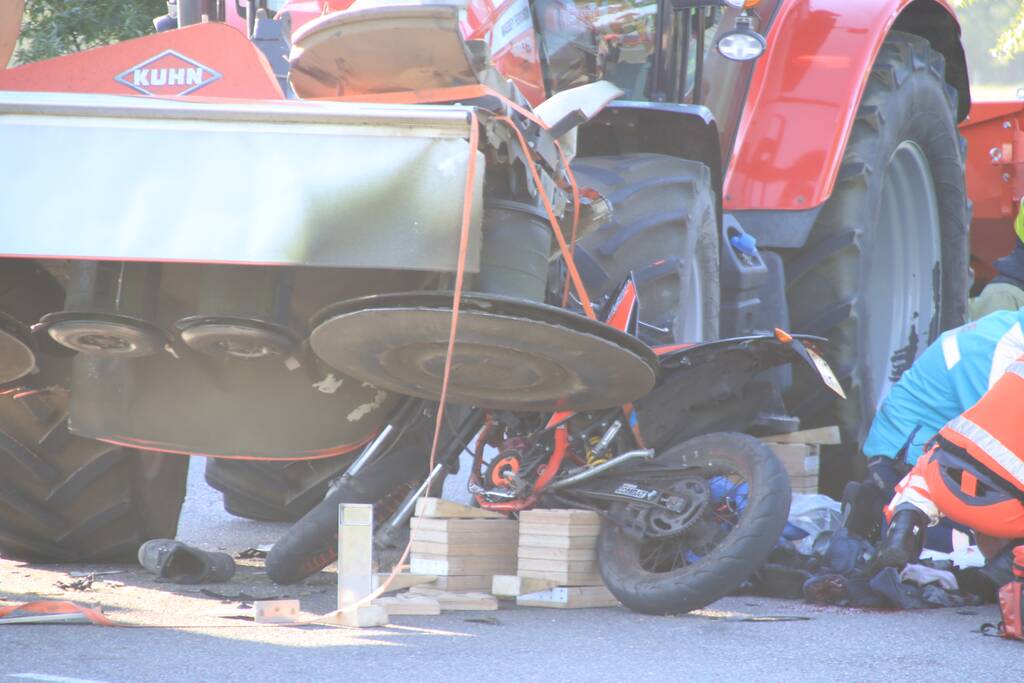 Scooter en scooterrijder bekneld onder tractor na ongeval