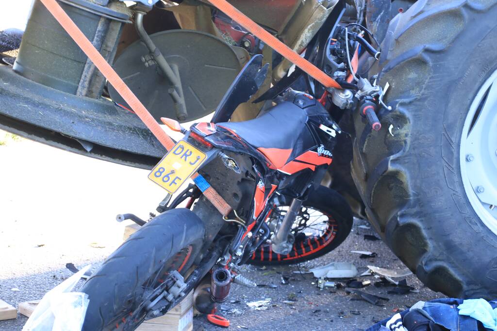 Scooter en scooterrijder bekneld onder tractor na ongeval