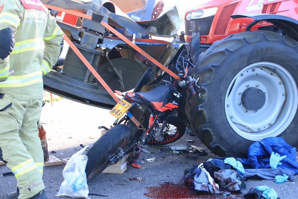 Scooter en scooterrijder bekneld onder tractor na ongeval