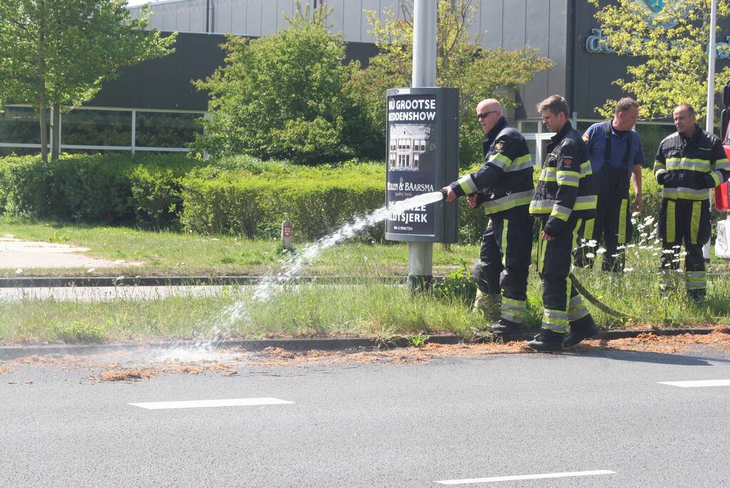 Brandweer blust brandend gras in berm