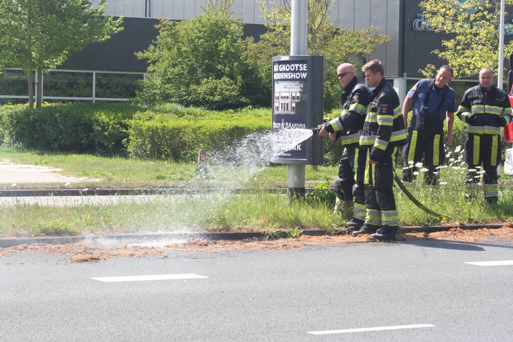 Brandweer blust brandend gras in berm