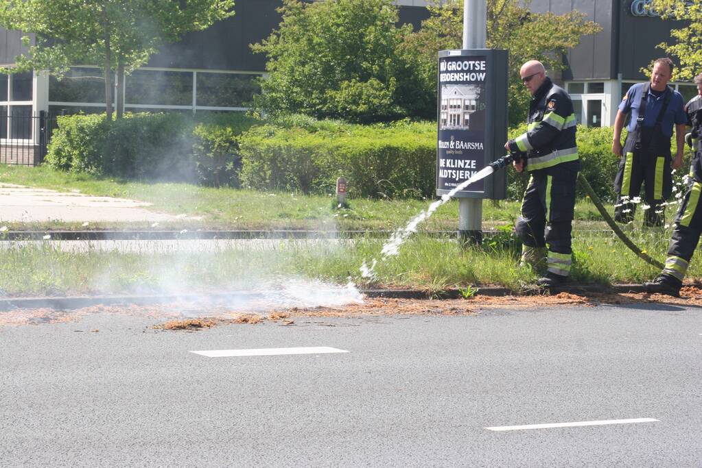 Brandweer blust brandend gras in berm