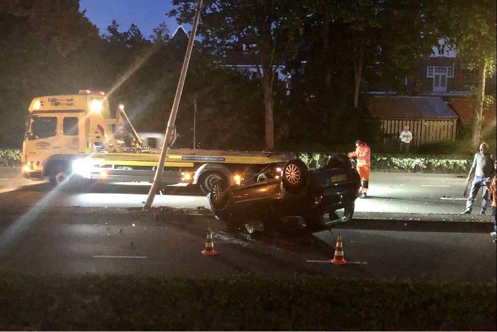 Auto knalt op lantaarnpaal en belandt op de kop
