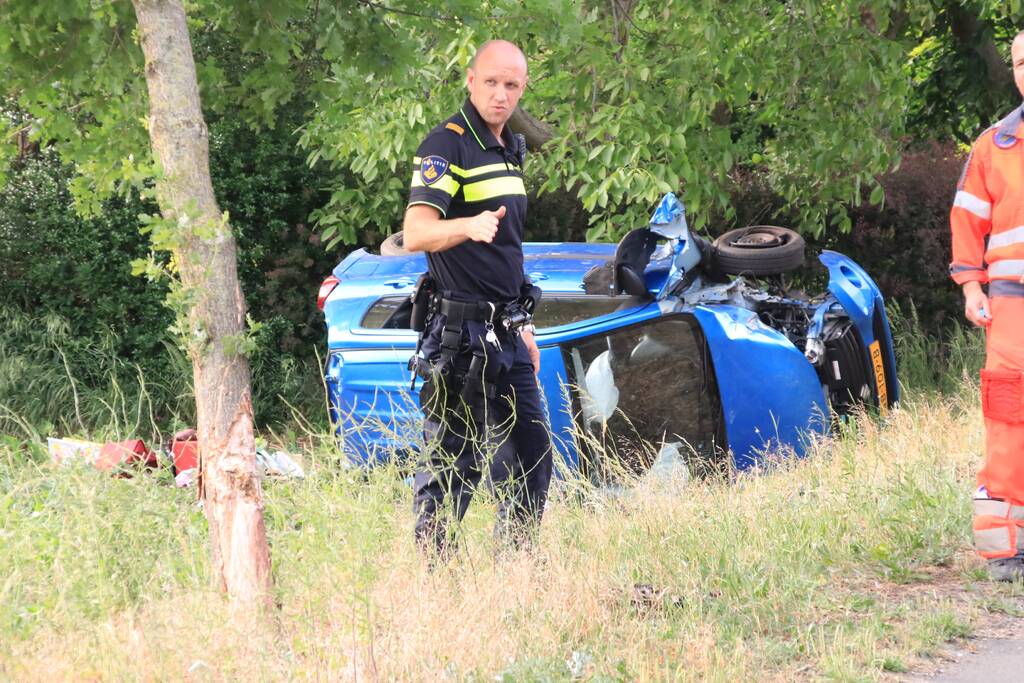 Auto belandt op zijn kant in weiland