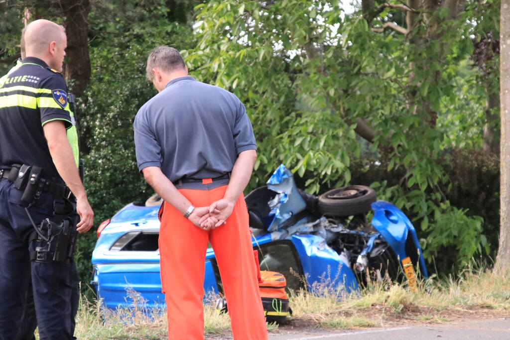 Auto belandt op zijn kant in weiland